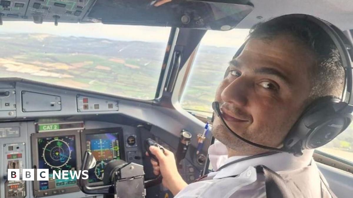 Mr Abbasi, sitting in the cockpit of an aircraft in front of the control system. He wears a pilot's shirt and earpiece and is flying the plane in this picture.