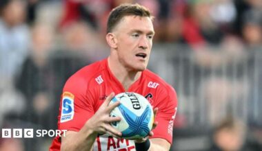 Dallas McLeod holds the ball in two hands in front of him while on the pitch during a match for Crusaders