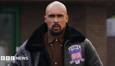 Ashley Warren outside court wearing a brown shirt and a black leather jacket. He is scowling at the camera.