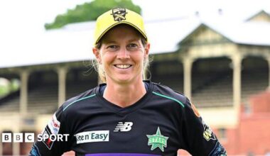 Meg Lanning looking straight at the camera with a big smile and wearing a black Melbourne Stars kit