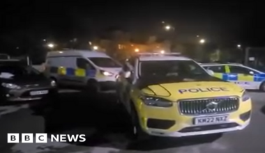 Three police vehicles inside a car-park at night time.