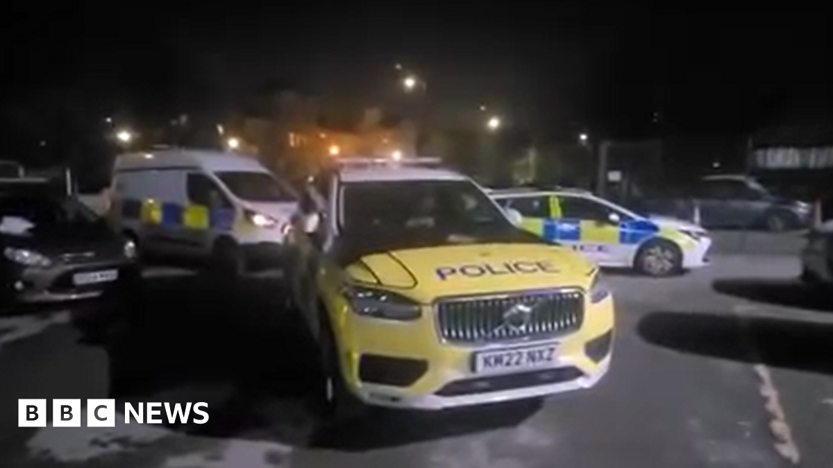 Three police vehicles inside a car-park at night time.