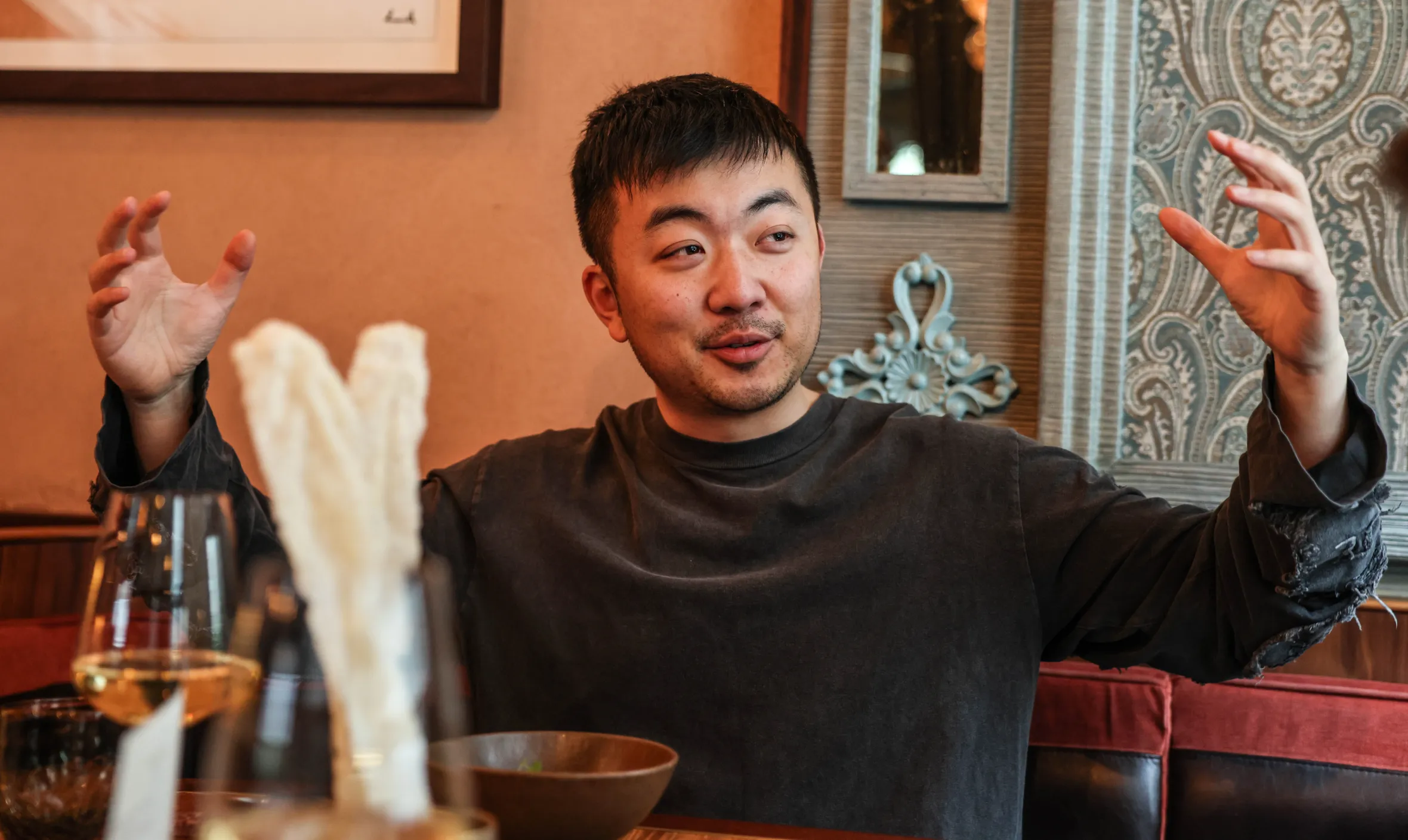 Carl Pei, Founder and CEO of Nothing, gesticulating while seated in Bibi restaurant.