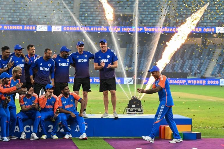 India's captain Suryakumar Yadav (R) playfully pretends to hold the trophy as his team celebrates their victory at the end of the Asia Cup 2025 Twenty20 international cricket final match between India and Pakistan at the Dubai International Stadium in Dubai on September 28, 2025. (Photo by Sajjad HUSSAIN / AFP)