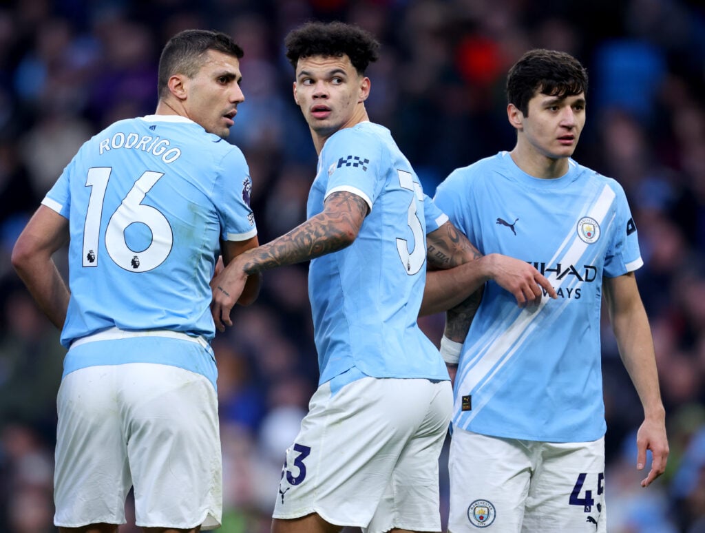 Nico O'Reilly of Manchester City forms a defensive wall with Rodri and Abdukodir Khusanov
