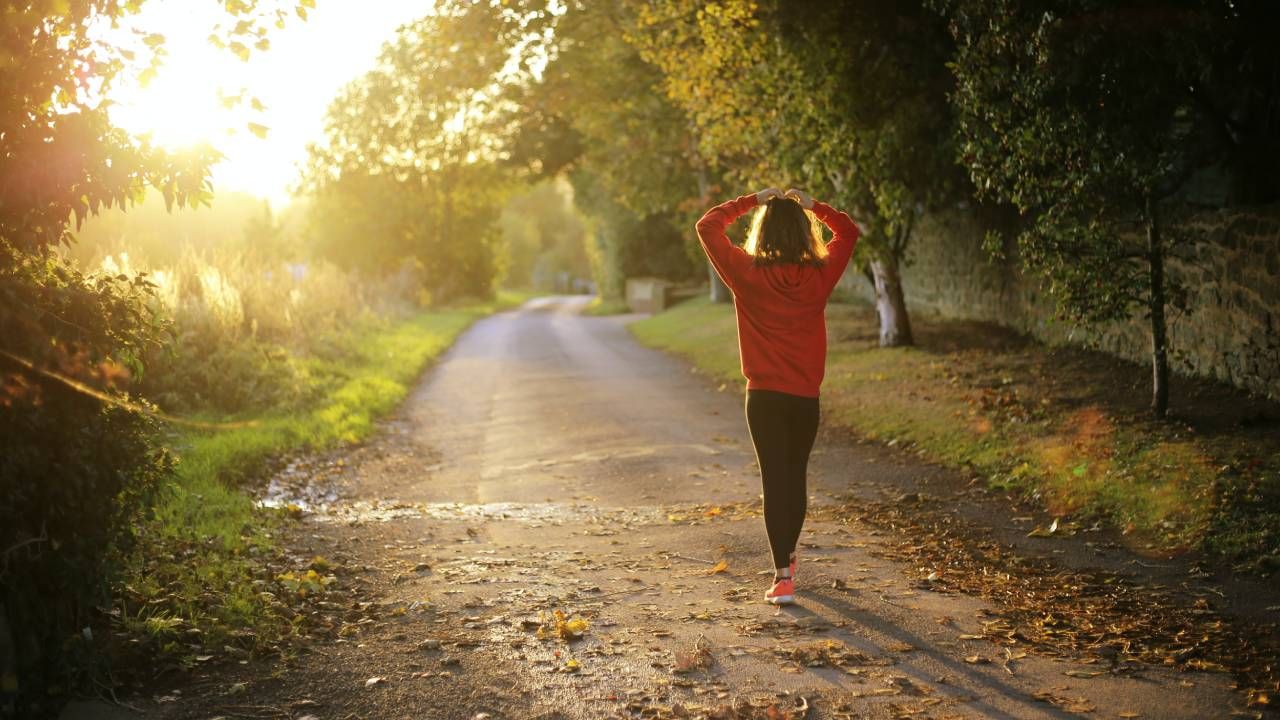 Woman in an orange jumper walking through the woods