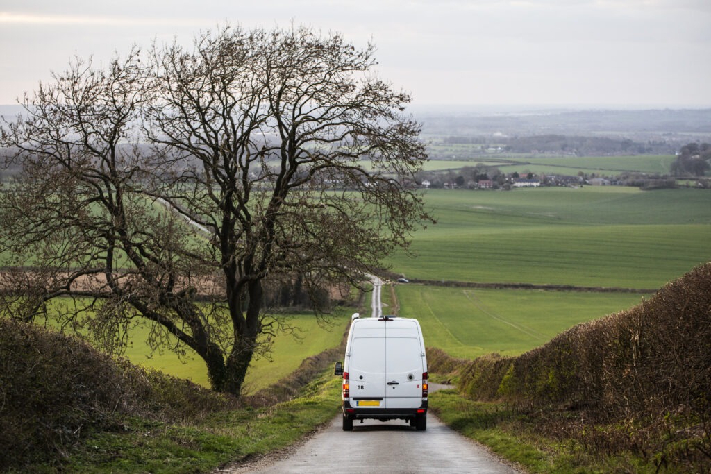 Photo of a white van driving down a country road in the UK.