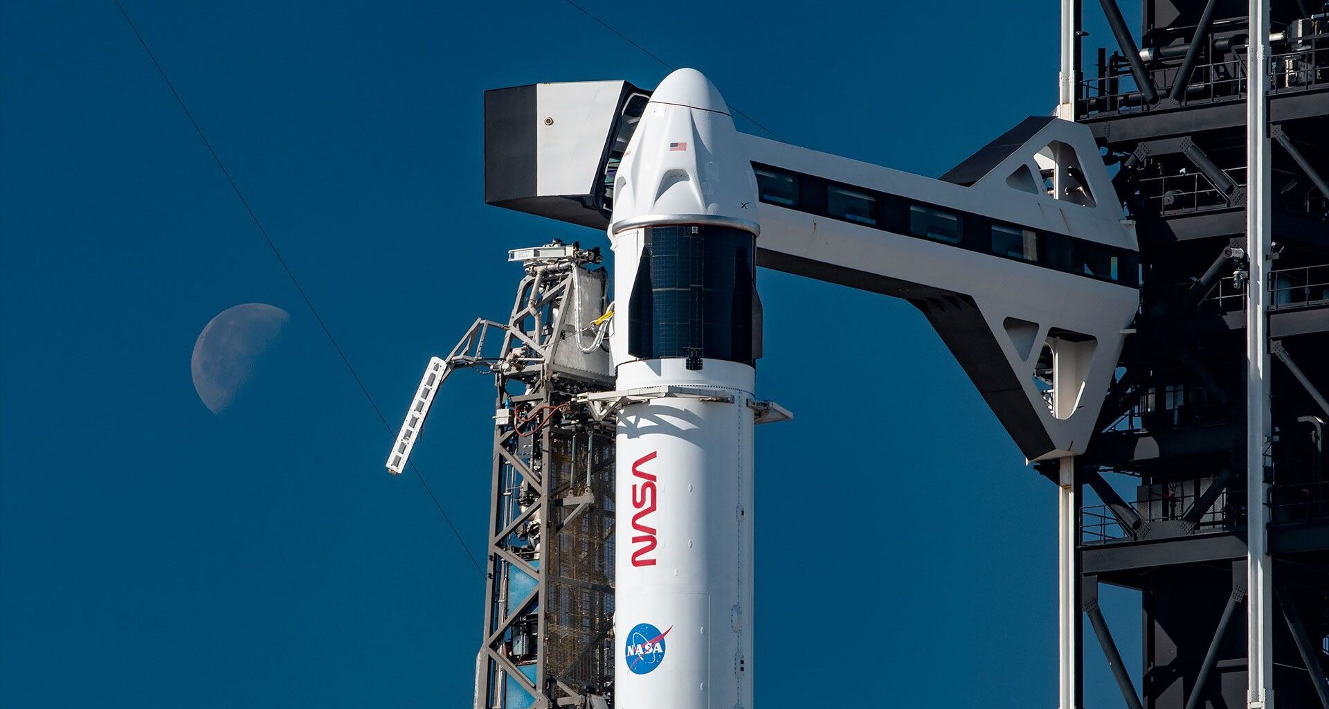 a white and black rocket with NASA markings on it stands poised on a launch pad awaiting its day to launch