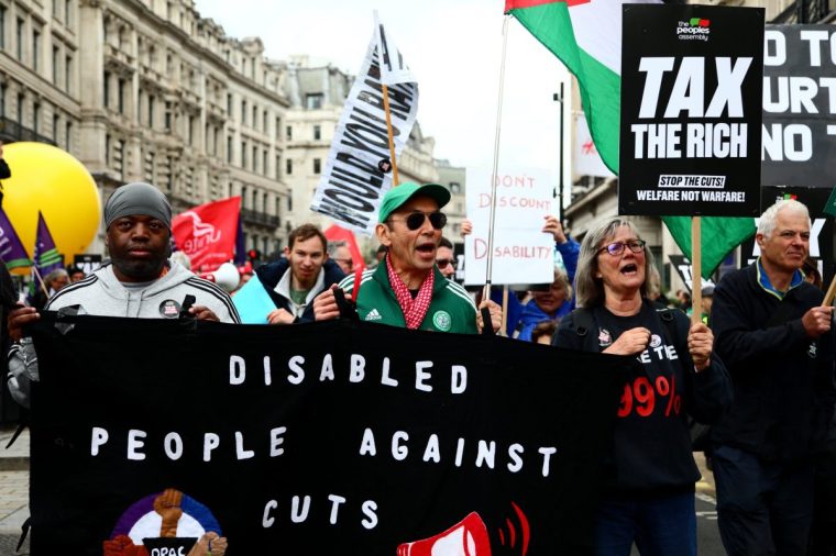LONDON, ENGLAND - JUNE 7: Activists hold a banner against disability benefit cuts during a protest over benefits cuts organised by People's Assembly on June 7, 2025 in London, England. Activists as well as some Labour MPs have objected to the government's proposed benefits cuts, including tightened criteria for personal independence payments (Pip) for people with disabilities. (Photo by Alishia Abodunde/Getty Images)