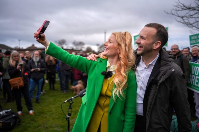 DENTON, ENGLAND - FEBRUARY 07: Green Party leader, Zack Polanski, and Candidate, Hannah Spencer, take a selfie during a campaign event ahead of the Gorton and Denton By-election on February 7, 2026 in Denton, England. Green Party Candidate, Hannah Spencer, s a 34-year-old professional plumber and councillor who currently leads the Green Party group on Trafford Council. Her campaign emphasises her working-class roots, with the slogan 