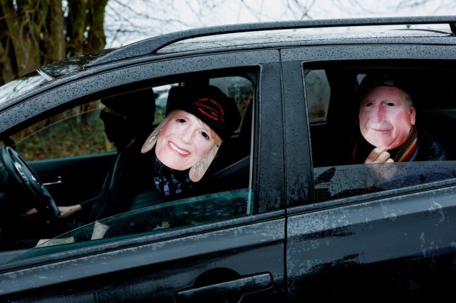 Members of the Norfolk Suffolk Hunt Saboteurs wear masks representing King Charles and Queen Camilla outside the Sandringham Estate, after Andrew Mountbatten-Windsor, younger brother of Britain's King Charles, formerly known as Prince Andrew, was released following arrest on suspicion of misconduct in public office on Thursday, after the U.S. Justice Department released more records tied to the late financier and convicted sex offender Jeffrey Epstein, in Norfolk, Britain, February 21, 2026. REUTERS/Benoit Tessier