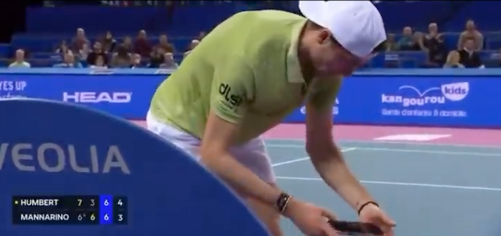 Tennis player Ugo Humbert checks his phone mid-match.