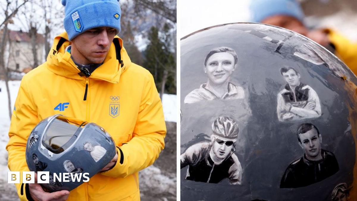 Ukraine's skeleton racer Vladyslav Heraskevych holds his helmet, which depicts victims of his country's war with Russia,