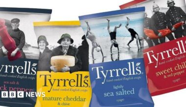 Four bags of crisps places next to each other on a white background. From left to right, the bags are black, yellow, blue and red.