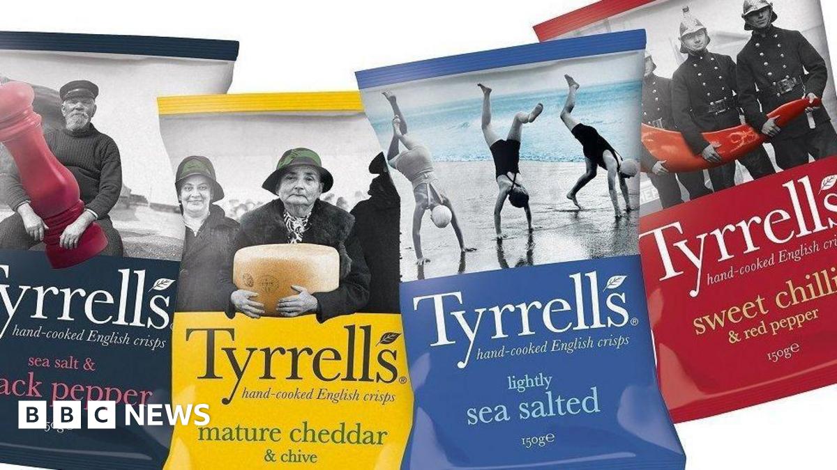 Four bags of crisps places next to each other on a white background. From left to right, the bags are black, yellow, blue and red.