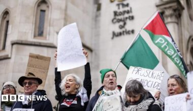 Several people hold placards and celebrate outside the court