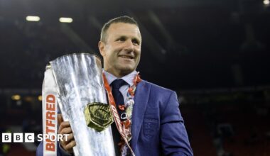 Willie Peters holds a rugby ball, with an Australia player in the background