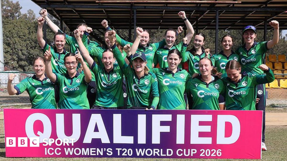 Ireland players celebrate in front of a sign that reads 'qualified: ICC Women's T20 World Cup 2026'