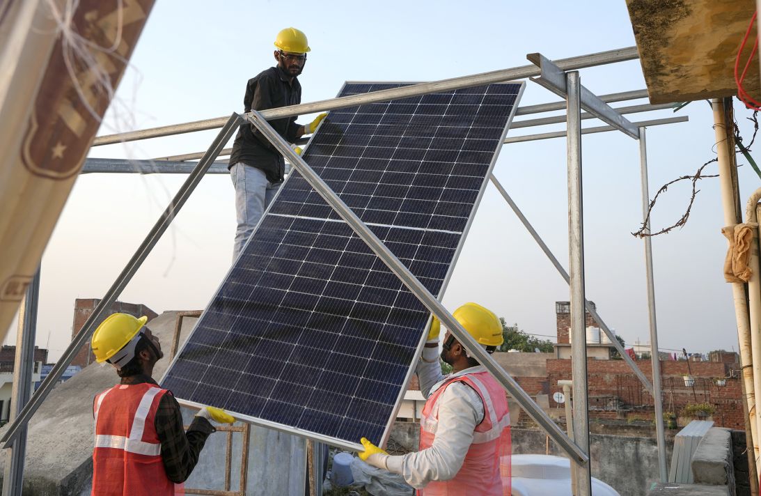 Solar installers set up a rooftop solar panel system on a house in Prayagraj, India, on October14, 2024.