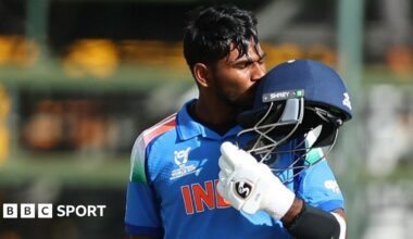 Aaron George celebrates his century by kissing his helmet