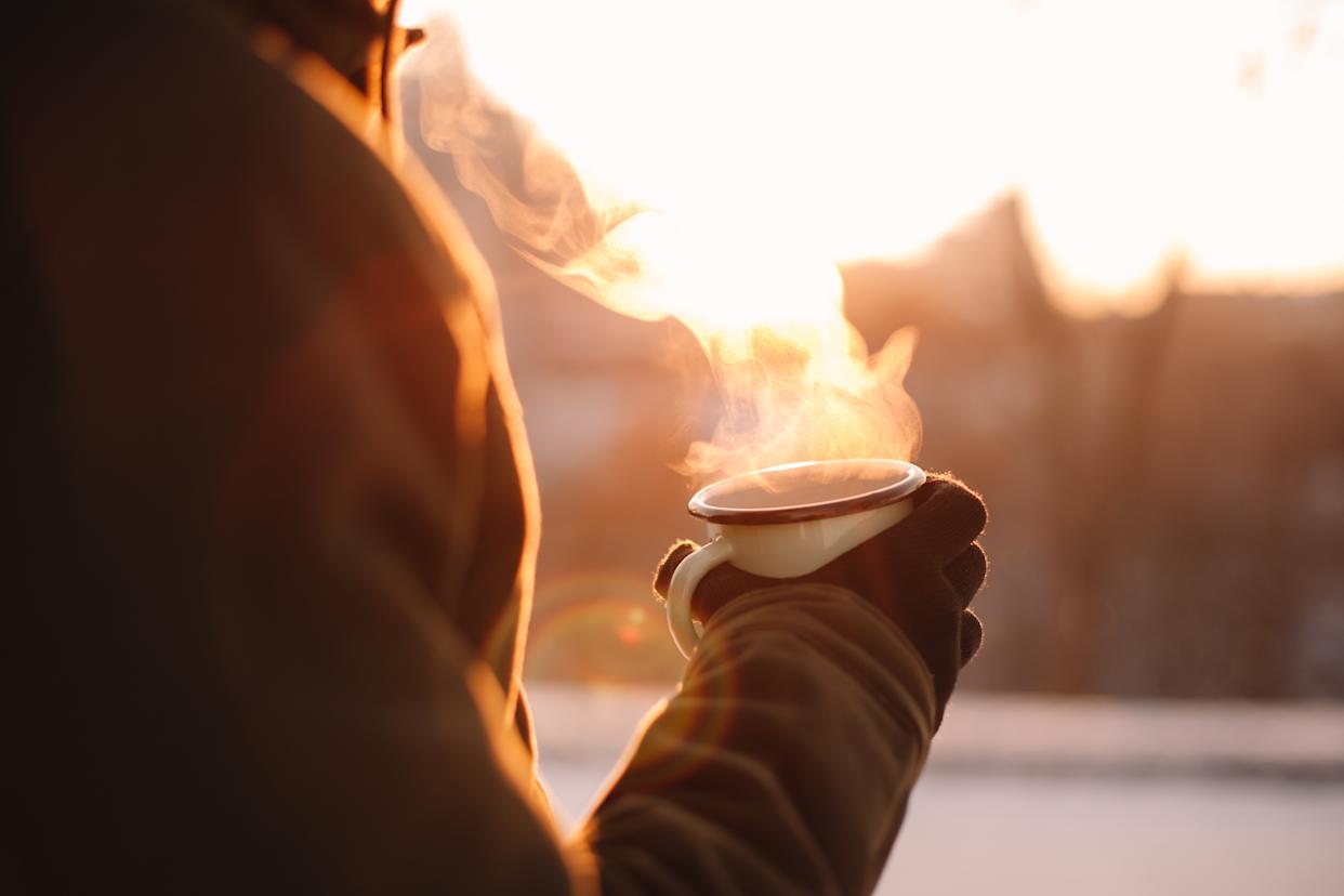Man holding mug with hot drink outdoors in winter during frosty weather