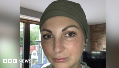 A woman looking down the lens of the camera. She is expressionless.