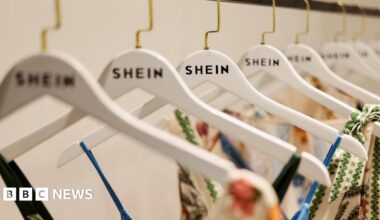 Shein founder Xu Yangtian, or Sky Xu, speaks to an audience during the Provincial High-quality Development Conference. He is standing behind a lectern while dressed in a navy suit and burgundy tie.