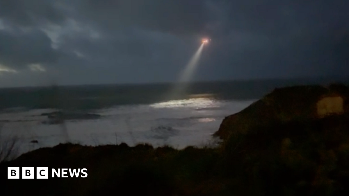 A helicopter with a strong search line flies over Newqyay