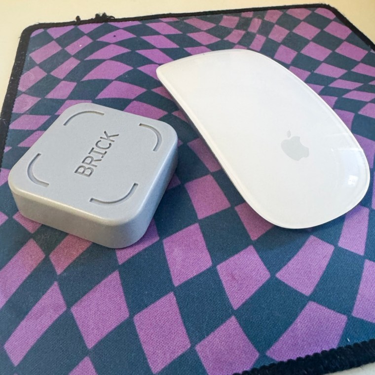 A photo of The Brick on a desk next to an Apple Magic Mouse.