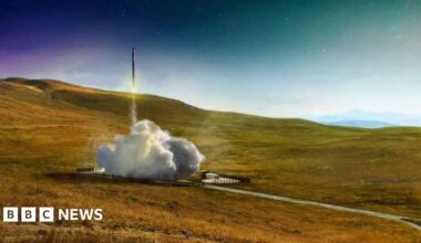 An aerial image of SaxaVord spaceport under construction on the island of Unst in Shetland. There is a launch pad with a launch tower on a flat area of land above sheer cliffs to the sea below.