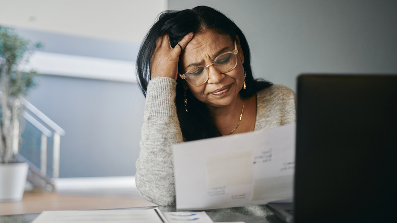Stressed senior women looking at document.