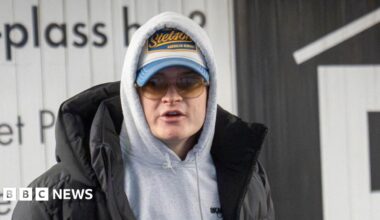 A sketch shows a young man in white and glasses flanked by two people in darker clothing