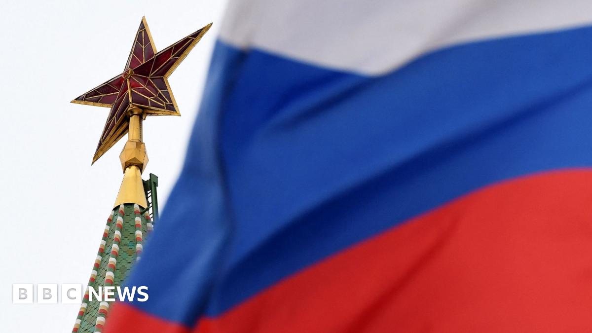 A grab from video depicts Dr Read speaking to the camera while standing outside next to a brick building and red railings, with the text 'hello, I'm Alan Read,' overlain in the bottom as subtitles.
