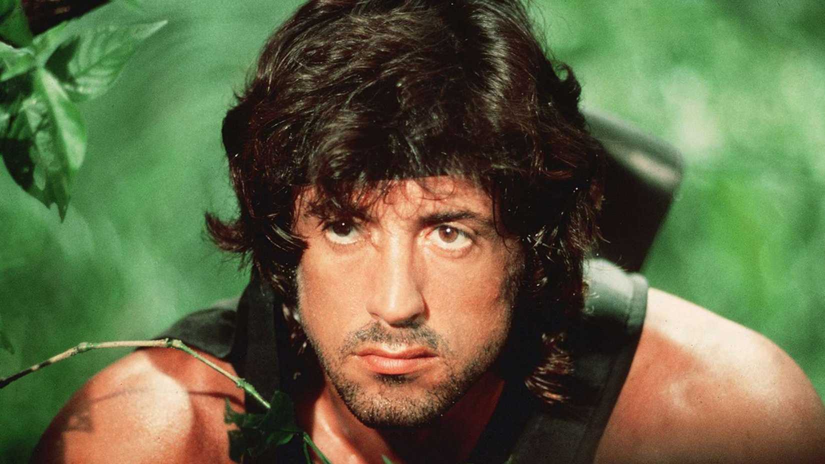 Close up of Sylvester Stallone as Rambo as he peers through foliage