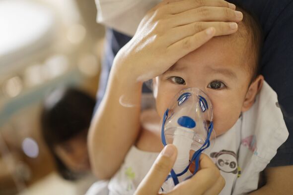 Concern Asian Mother embracing her Toddler son for Inhalation medicine theraphy by the nebulizer mask