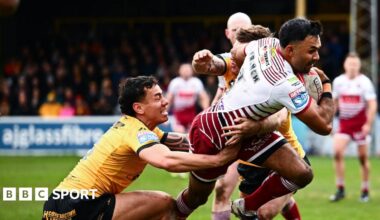 Wigan's Bevan French (right) has the ball in his right hand as two Castleford players including Daejarn Asi (left) try to tackle him