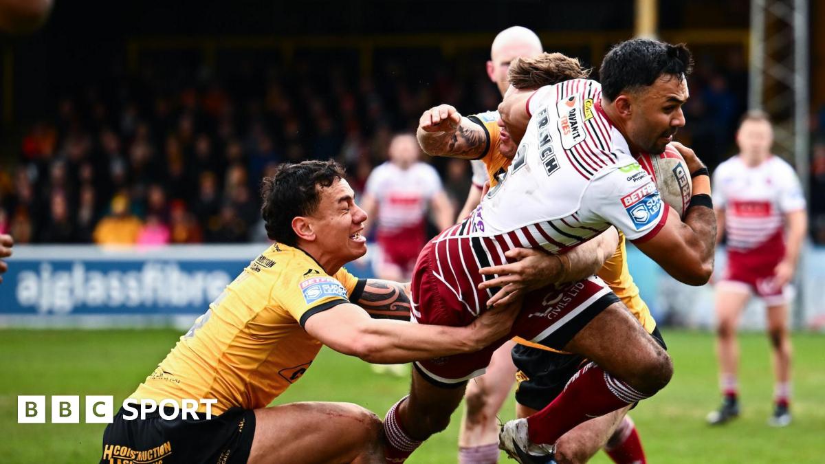 Wigan's Bevan French (right) has the ball in his right hand as two Castleford players including Daejarn Asi (left) try to tackle him