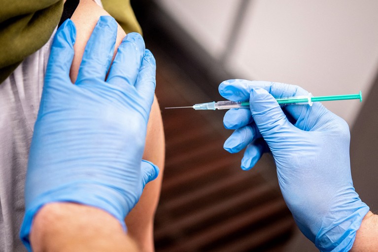 A close up view of a woman's arm as she receives a vaccination with the Astrazeneca vaccine.