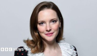 Headshot of Morfydd. She has brunette hair and wears an off-shoulder black dress