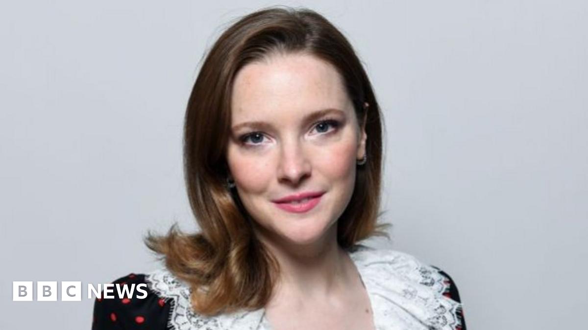 Headshot of Morfydd. She has brunette hair and wears an off-shoulder black dress