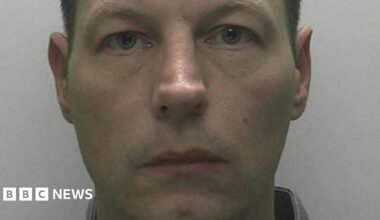 A mugshot of Redmond with short dark hair and a white-ish background.