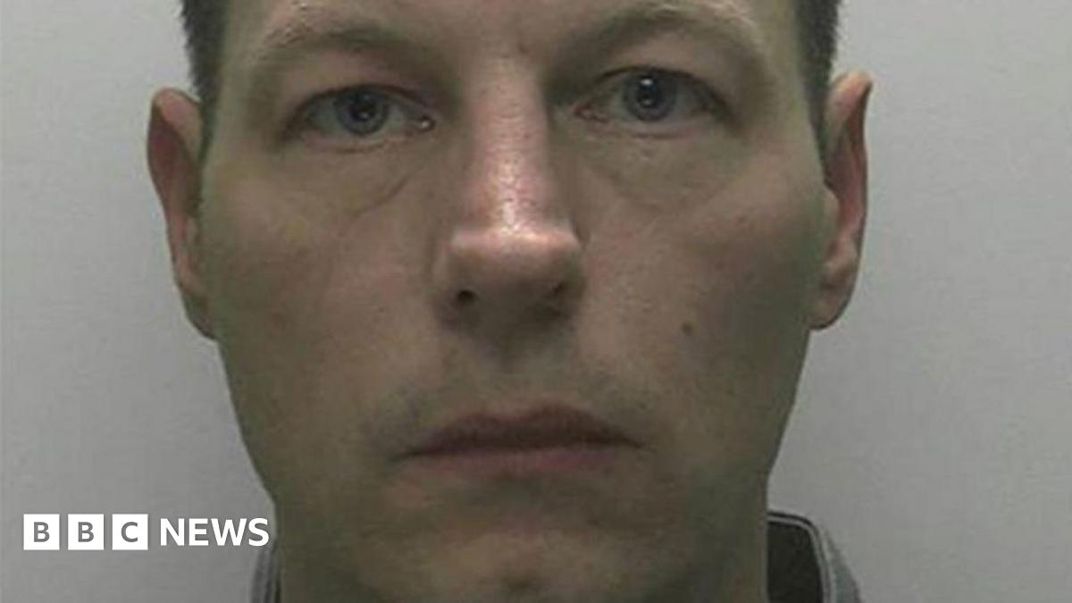 A mugshot of Redmond with short dark hair and a white-ish background.