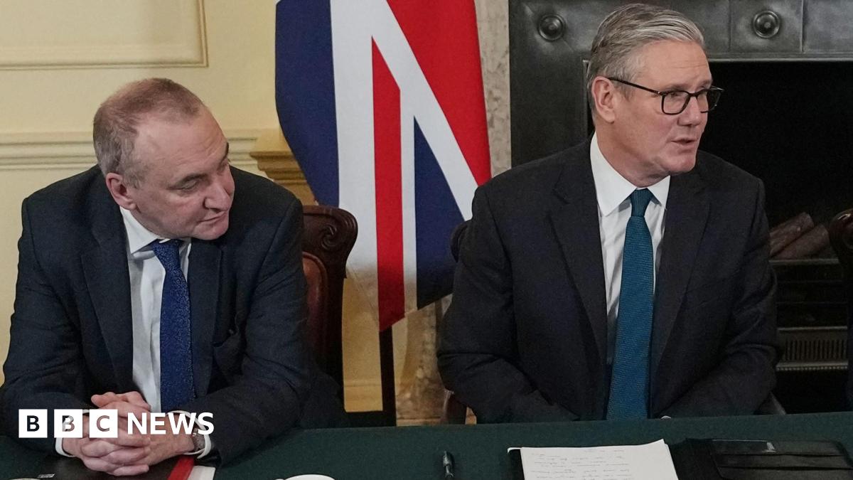 Sir Chris Wormald looks sideways at Sir Keir Starmer at the cabinet table with a union jack behind them