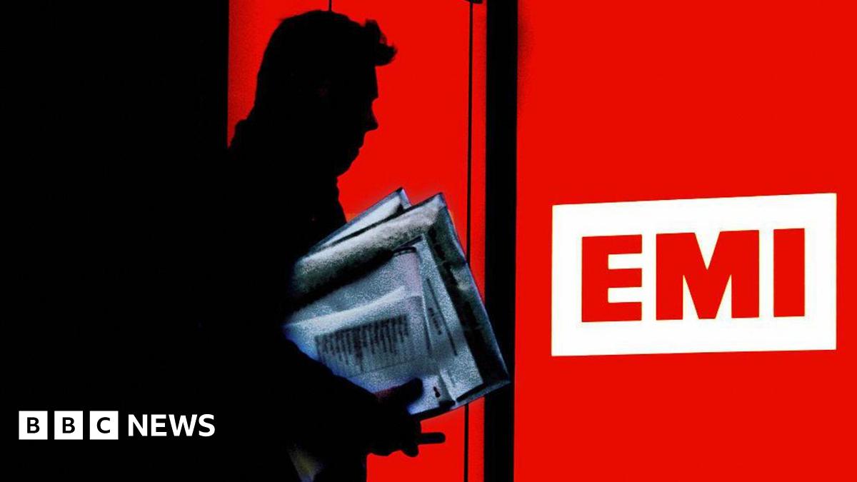 A Silhouette of a man carrying a bundle of papers walking out of the door of the EMI record company in London. The EMI logo of three letters on a white background is surrounded in red.