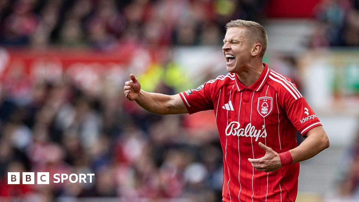 Oleksandr Zinchenko shouting and raising his right arm as he gives directions. He has short, fair hair and is wearing Nottingham Forest's red home shirt. It has white pin stripes, a club crest on its left breast, an Adidas logo on the other side and a Bally's sponsorship logo across the chest.
