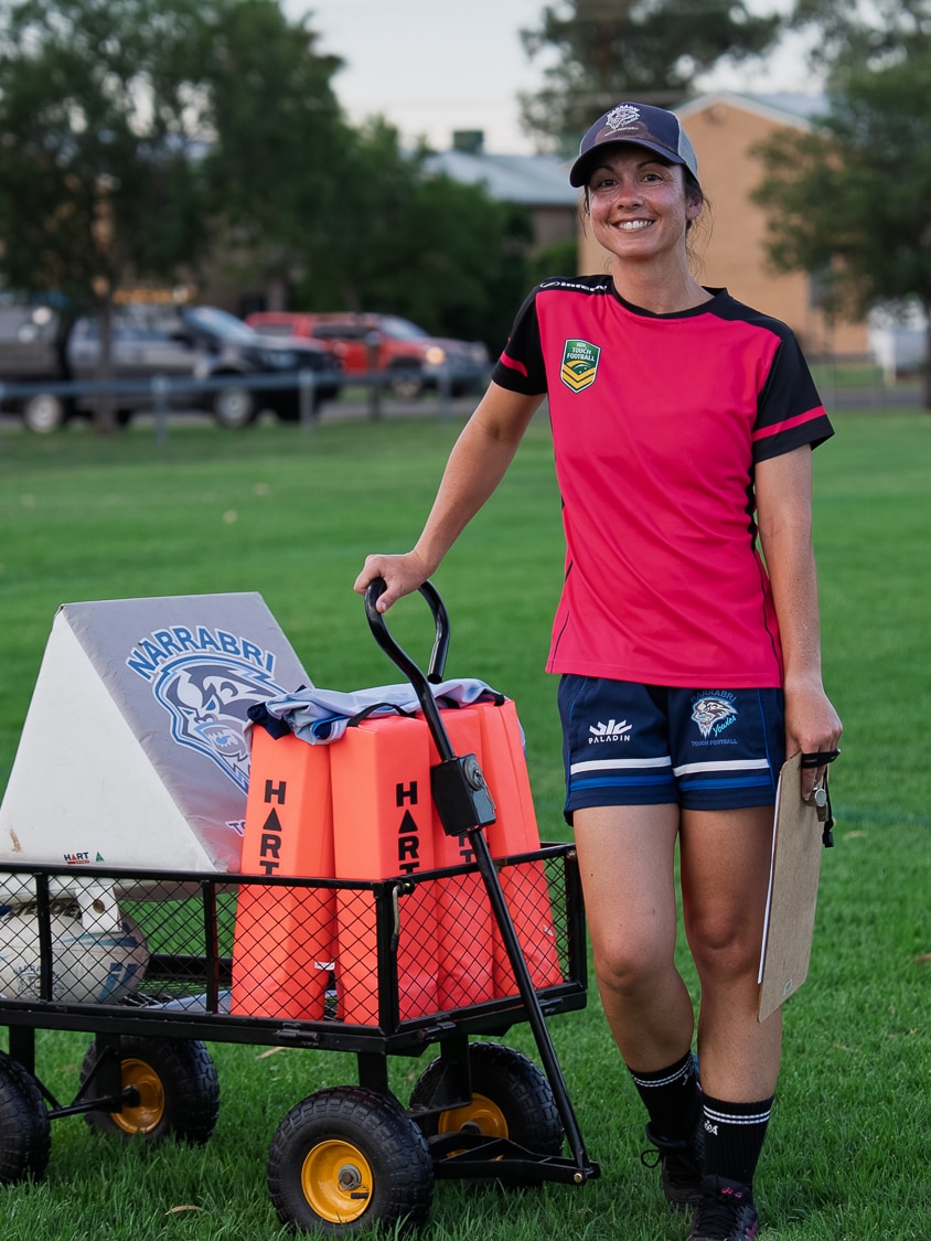A young woman in sports gear with a trolly of football things