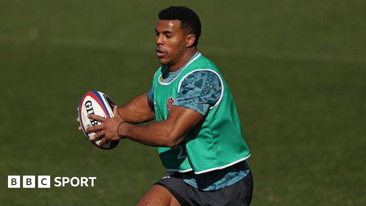 Immanuel Feyi-Waboso running with the ball during an England training camp. He has short black hair and is wearing a green bib with a blue training top and shorts.