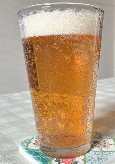 The tinnie pours a crystal clear, amber hue with a frothy head.