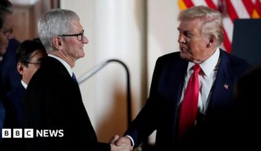 Two men wearing suits shake hands.