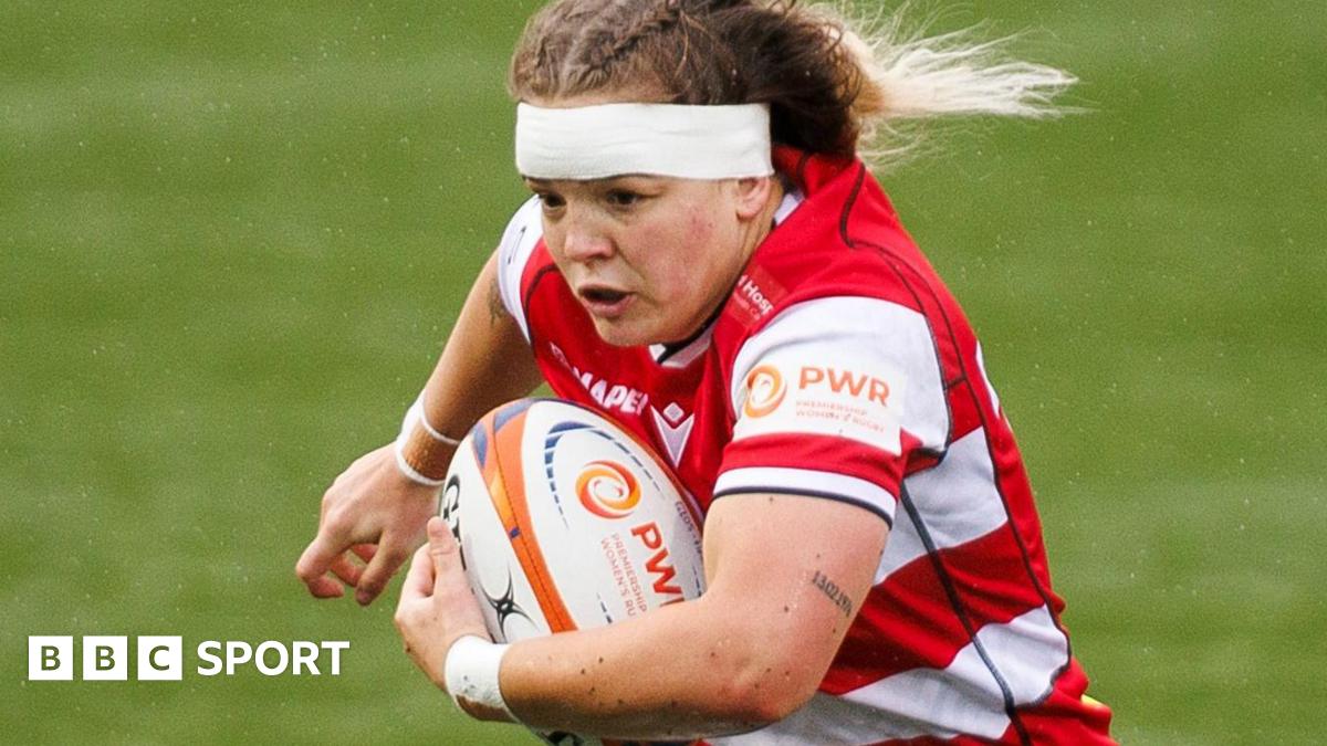 Georgia Brook playing for Gloucester-Hartpury in their red and white shirt, running with the ball under her left arm